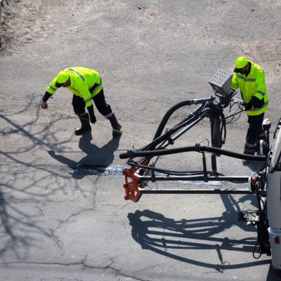 Road surface restoration work. The worker performs on road patcher work on the repair of cracks by filling and sealing with coated by bitumen emulsion and dry aggregate in the asphalt surface.