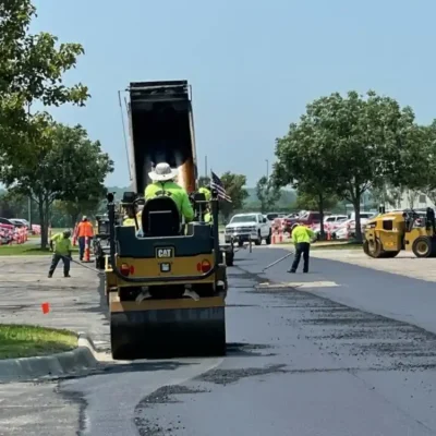 man sitting on asphalt sealer laying fresh asphalt